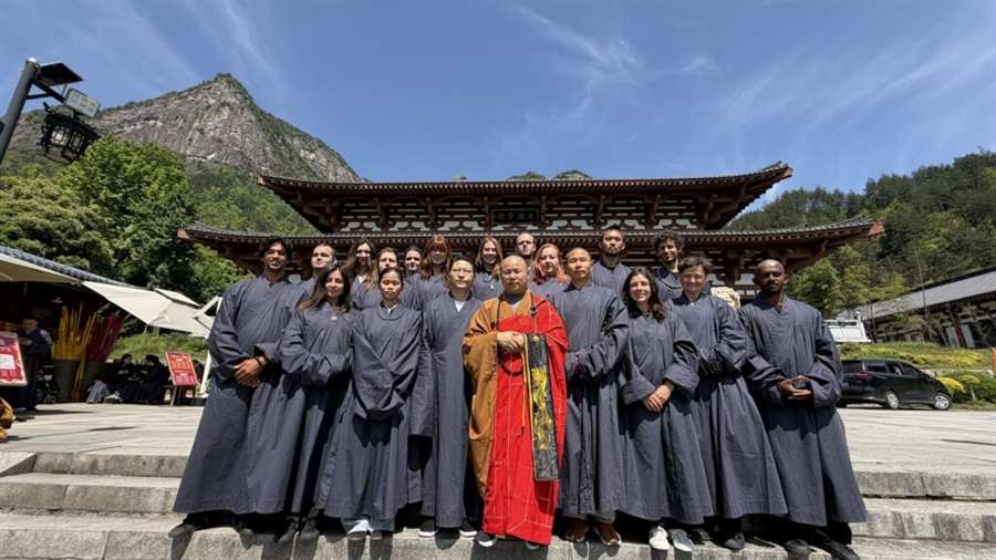 The 2025 cohort of twenty students with Shifu Shi Yanjun outside the temple gate