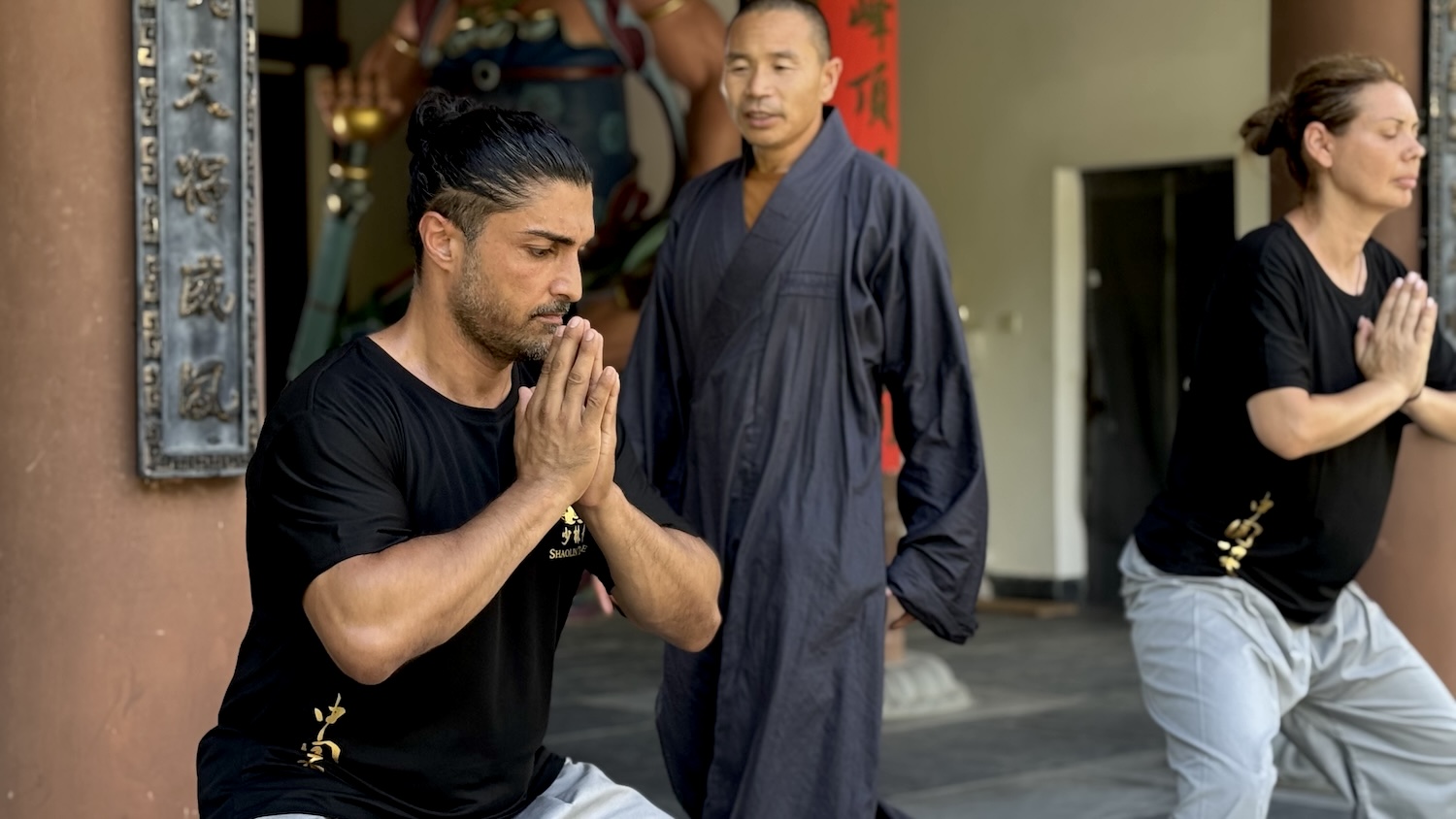 A student training in a horse stance under the guidance of a Shaolin monk